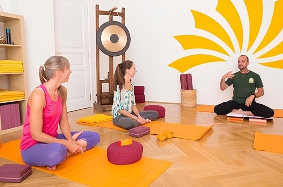 3 Personen im Schneidersitz in einem Mattenraum